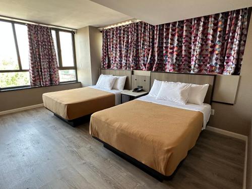 a hotel room with two beds and two windows at Regal Inn & Suites New York LaGuardia Hotel in Flushing