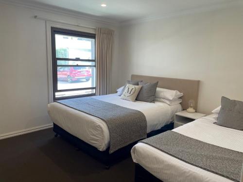 a hotel room with two beds and a window at Millthorpe Motel in Millthorpe