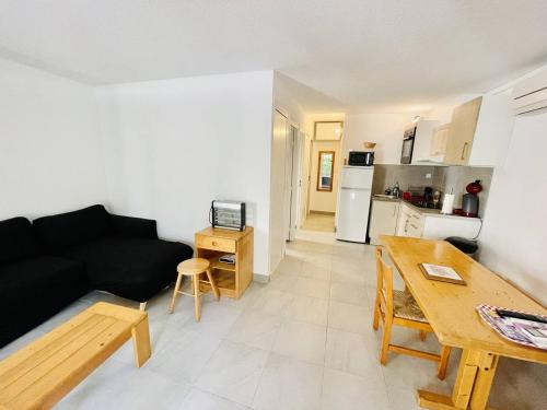 un salon avec un canapé noir et une table dans l'établissement Appartement Climatisé en Rez-de-Jardin avec Parking, à 50m de la Plage de la Roquille - FR-1-723-117, au Cap d'Agde