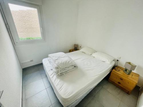 un petit lit dans une chambre avec une fenêtre dans l'établissement Appartement Climatisé en Rez-de-Jardin avec Parking, à 50m de la Plage de la Roquille - FR-1-723-117, au Cap d'Agde