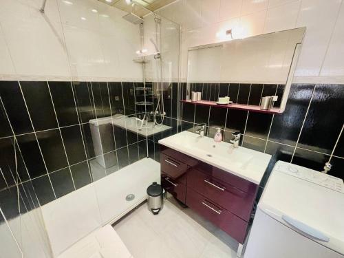 une salle de bain avec un lavabo, une baignoire et un miroir dans l'établissement Appartement Climatisé en Rez-de-Jardin avec Parking, à 50m de la Plage de la Roquille - FR-1-723-117, au Cap d'Agde