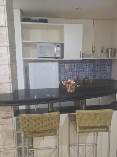 a kitchen with a black counter and two bar stools at Flat Number One - Fonseca Imóveis in São Luís