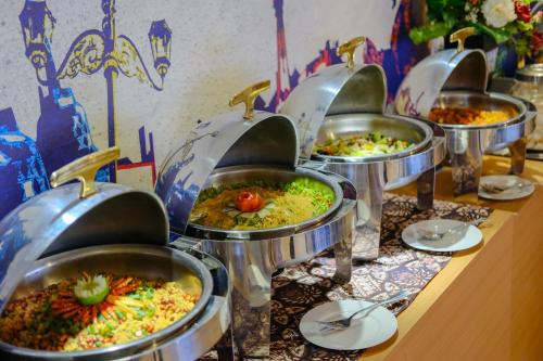 a row of trays filled with different types of food at Student Park Hotel in Yogyakarta