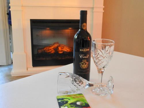 una botella de vino sentada en una mesa con una copa en Romance Chalet on Gallery Walk with Spa, Fireplace, WiFi & Netflix en Mount Tamborine