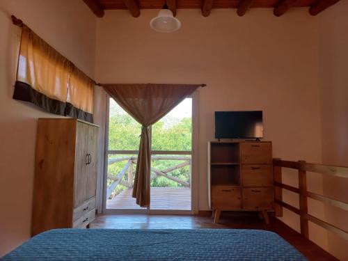a bedroom with a bed and a window with a television at Cabaña La Yumba in Capilla del Monte