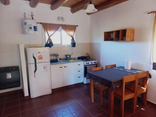 a kitchen with a table and a white refrigerator at Cabaña La Yumba in Capilla del Monte