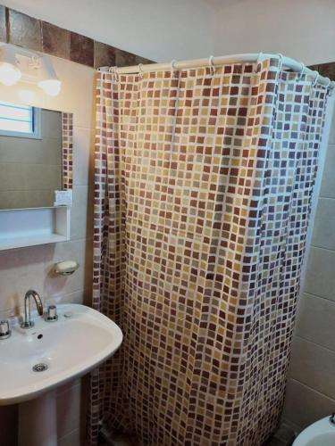 a bathroom with a shower curtain and a sink at Cabaña La Yumba in Capilla del Monte