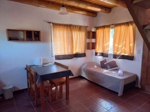 a bedroom with a bed and a table in a room at Cabaña La Yumba in Capilla del Monte
