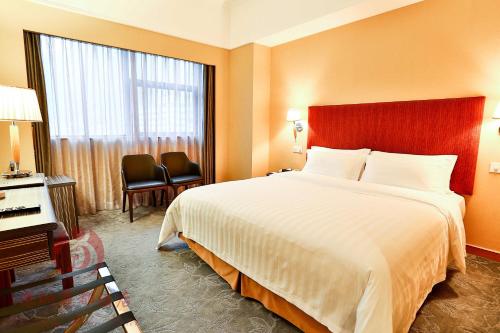 Cette chambre comprend un grand lit et une fenêtre. dans l'établissement Shenzhen Lido Hotel, à Shenzhen