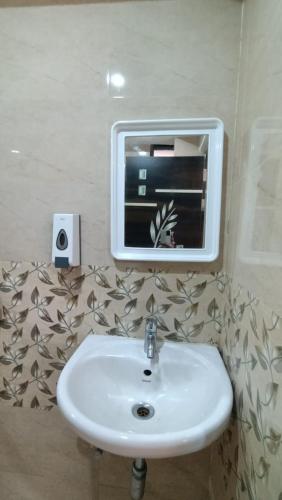 a bathroom with a sink and a mirror on the wall at HOTEL SUKHMANI in Guwahati
