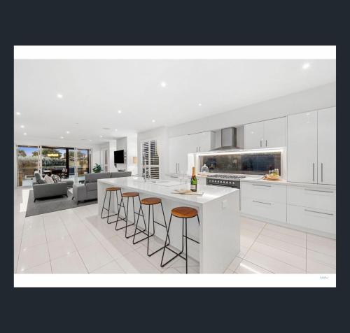 a kitchen with white cabinets and bar stools at St Georges Luxury Beach House in Torquay