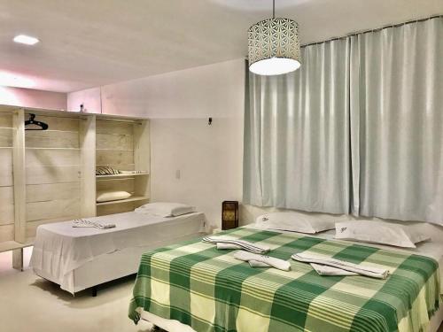 1 dormitorio con 2 camas y manta verde y blanca en Villa Jundu en São Miguel do Gostoso