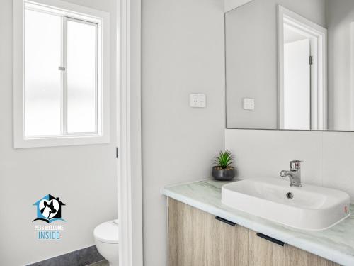 a white bathroom with a sink and a mirror at Brand New 3 Bed 2 Bath with Sea Views in Encounter Bay