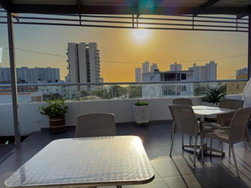 Un balcón con mesas y sillas y vista a una ciudad. en Hotel Zamay Gaira, en Santa Marta