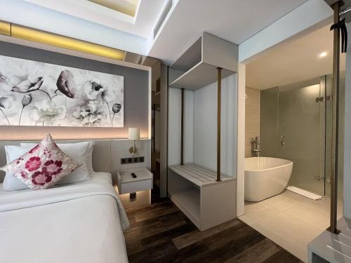 a bedroom with a bed and a bathroom with a tub at Arshika Bali Sunset Road in Kuta