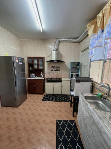 Una cocina con refrigerador de acero inoxidable y estufa. en Nurjah Homestay, en Kuala Terengganu