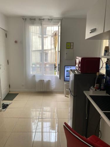 a kitchen with a refrigerator and a window at Paris Sud-porte de Gentilly mignon T2 250 m de Paris in Gentilly