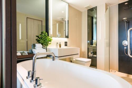 een badkamer met een groot wit bad en een wastafel bij The Siamese Hotel by PCL in Noord Pattaya