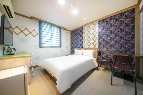 a bedroom with a large white bed and a chair at Sugar Motel in Gunsan