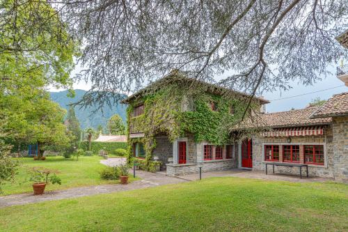 a stone house with red doors and a yard at Villa Colle in Ossuccio