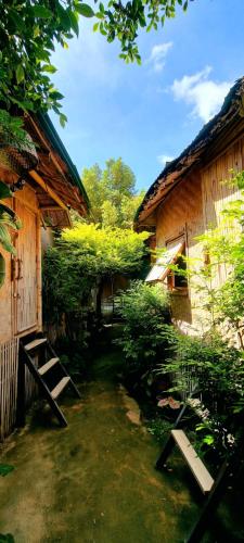 a garden with a bench and a building with trees at Fundee Story Guesthouse Bamboo House in Chiang mai old town in Chiang Mai