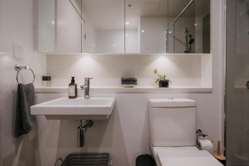 a white bathroom with a sink and a toilet at Twilight Olympic Park 2x King-beds Lux Apt in Sydney
