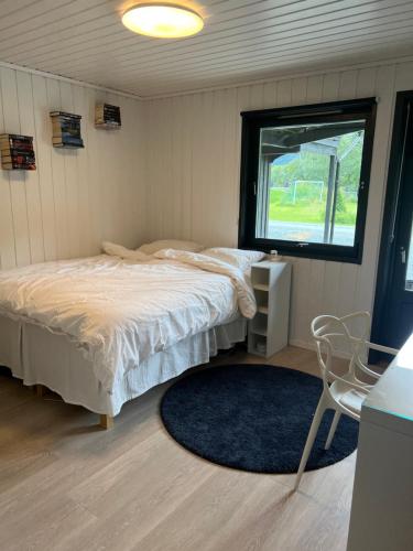 a bedroom with a bed and a window and a chair at Lykkja - Beautiful Waterfront House in Viggja