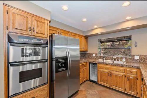a kitchen with wooden cabinets and stainless steel appliances at Arrowhead Lake Cabin pool table stunning views in Lake Arrowhead