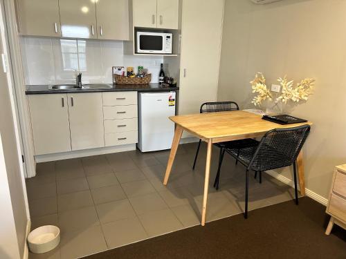 a kitchen with a wooden table and a white refrigerator at Millthorpe Motel in Millthorpe