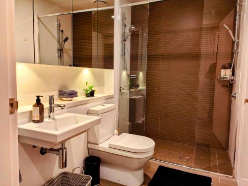 a bathroom with a toilet and a sink and a shower at Twilight Olympic Park 2x King-beds Lux Apt in Sydney