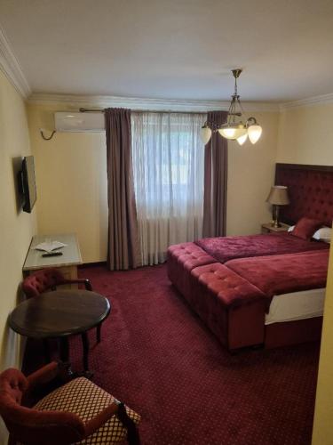 um quarto de hotel com uma cama vermelha e uma mesa em Matrix Hotel em Tecuci