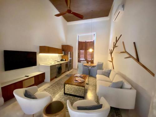 a living room with a couch and chairs and a tv at Las Lupitas Hotel Boutique in Campeche