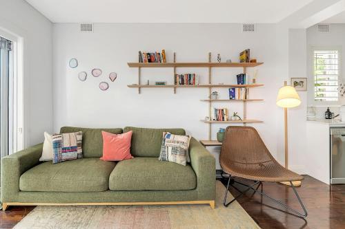 a living room with a green couch with pillows at 'Bronte Beauty' Modern Heritage Style with Balcony in Sydney