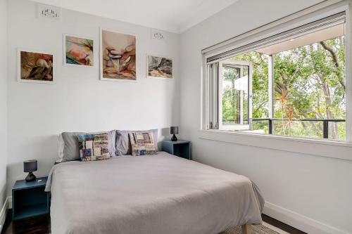 um quarto branco com uma cama e uma janela em 'Bronte Beauty' Modern Heritage Style with Balcony em Sidney