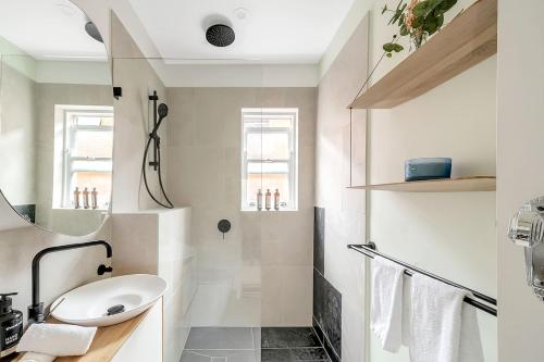 a white bathroom with a sink and a mirror at 'Bronte Beauty' Modern Heritage Style with Balcony in Sydney
