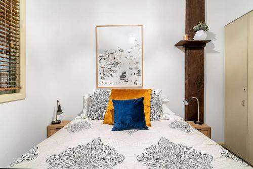 a bedroom with a bed with a blue pillow on it at The Stylist's House - A Chic Inner City Landmark in Sydney