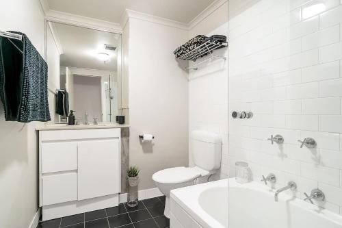 a white bathroom with a toilet and a shower at The Stylist's House - A Chic Inner City Landmark in Sydney