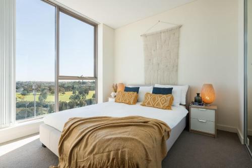 a bedroom with a large bed with a large window at 'The Peak' Resort-style Balcony Abode in the Metro in Sydney