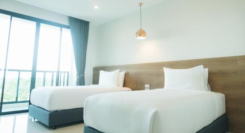 a hotel room with two beds and a window at Mountain&Sea Hotel Prachuap in Prachuap Khiri Khan