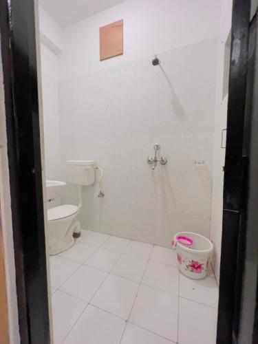 a white bathroom with a toilet and a bucket at Hotstel Udaipur in Udaipur