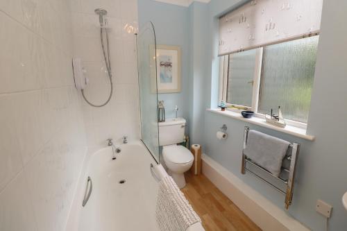 a bathroom with a tub and a toilet and a shower at Albert's Den in Falmouth