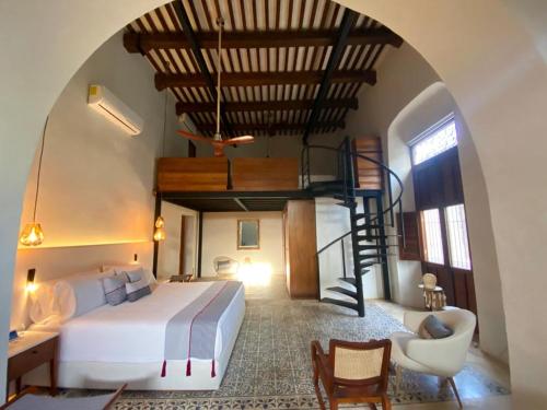 a bedroom with a bed and a spiral staircase at Las Lupitas Hotel Boutique in Campeche