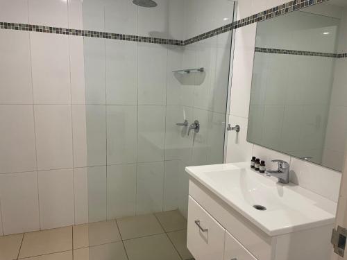 a white bathroom with a sink and a shower at Millthorpe Motel in Millthorpe