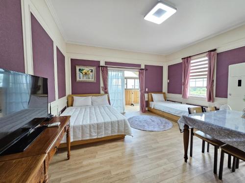 a large room with two beds and a television at Red Castle Pension in Jeju