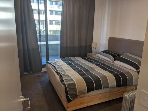 a bed in a room with a large window at New unit next to Myers in Canberra