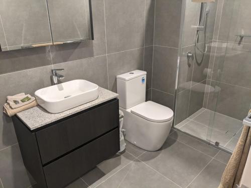 a bathroom with a toilet and a sink and a shower at New unit next to Myers in Canberra