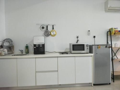 eine Küche mit einer Theke, einer Mikrowelle und einem Kühlschrank in der Unterkunft Studio 2-4pax/2mins LRT/Netflix/YSW Homes in Subang Jaya