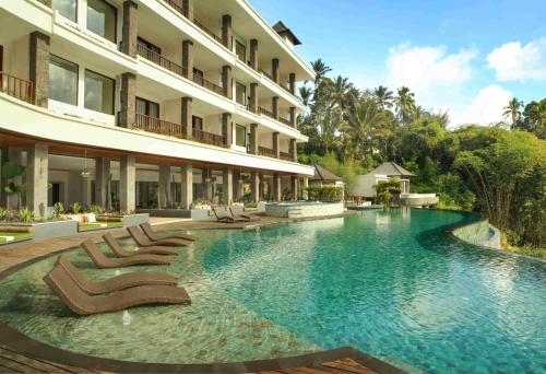 une piscine avec des chaises longues et un hôtel dans l'établissement Cicada Luxury Resort - Ubud, à Tegalalang