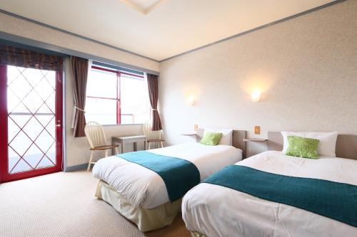 um quarto de hotel com duas camas e uma janela em Naughty Cao em Yamanakako
