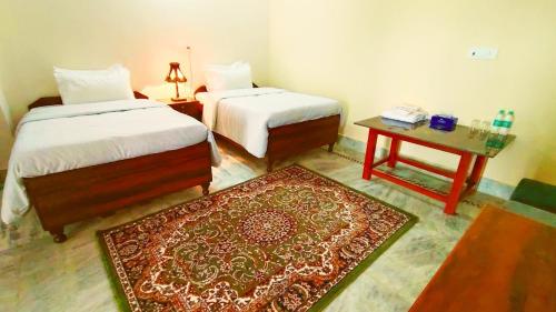 a room with two beds and a table with a rug at Casa Humana in Jaipur